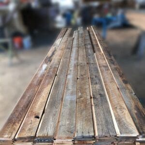 A stack of reclaimed wood planks in a workshop.