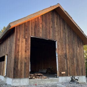 A barn with wood siding and concrete base.